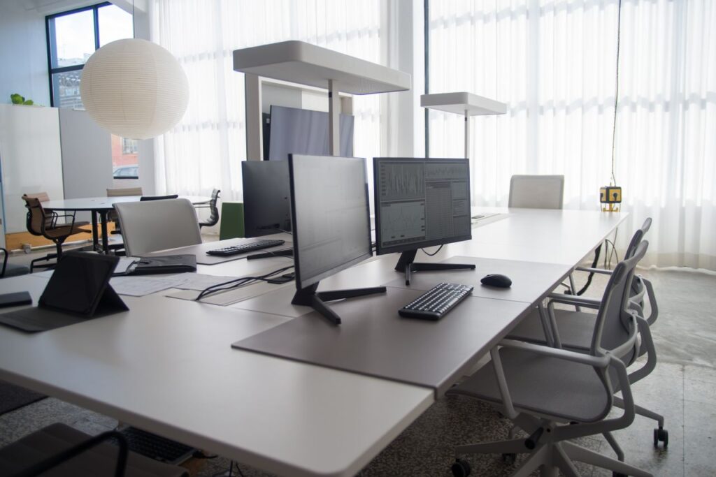 Spacious modern office featuring multiple computers, chairs, and collaborative workstations in natural light.